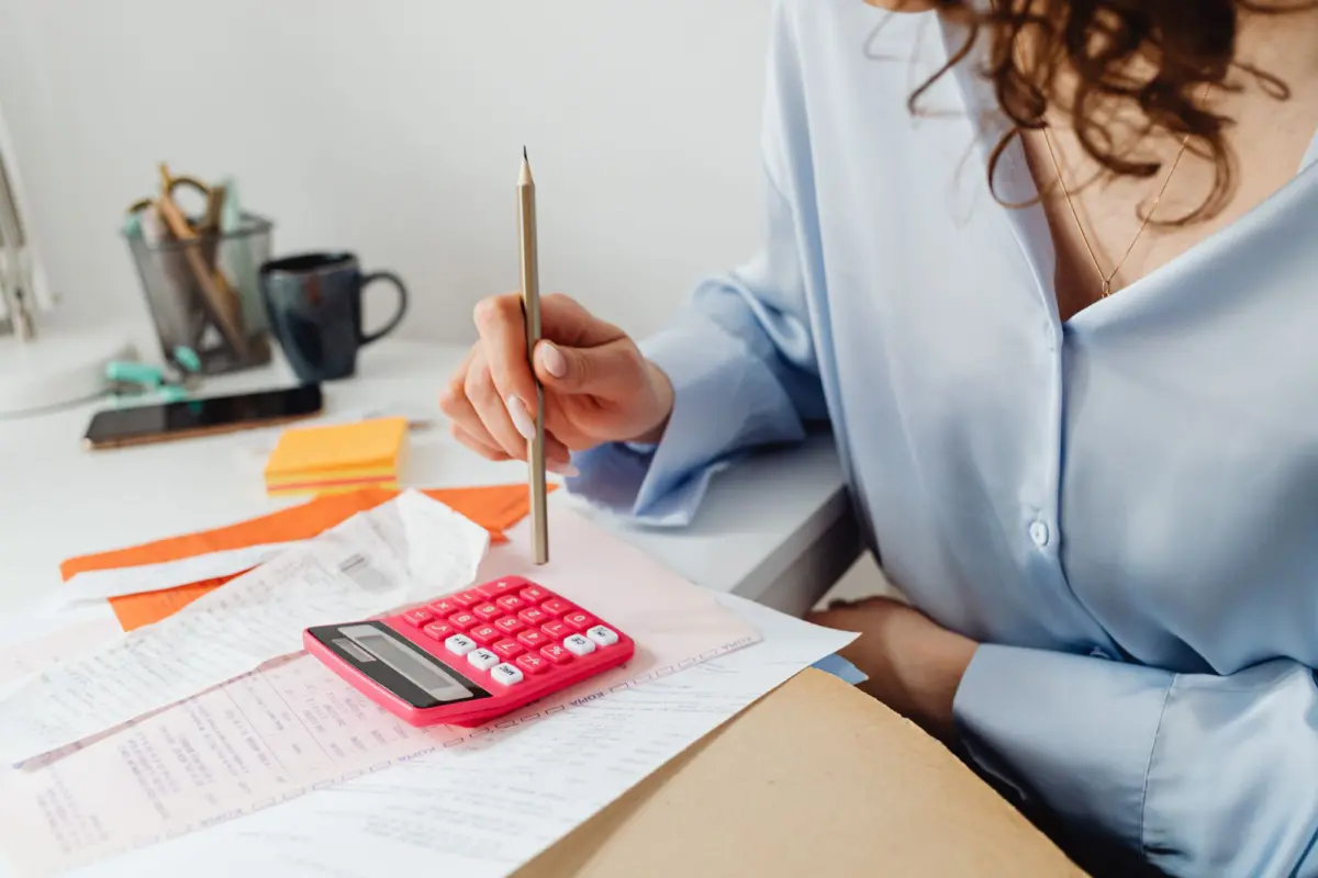 A woman adding up household expenses with a calculator